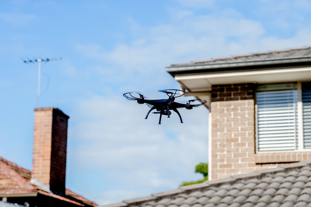 A drone flies towards the tiled roof of a residential house during an aerial property survey.